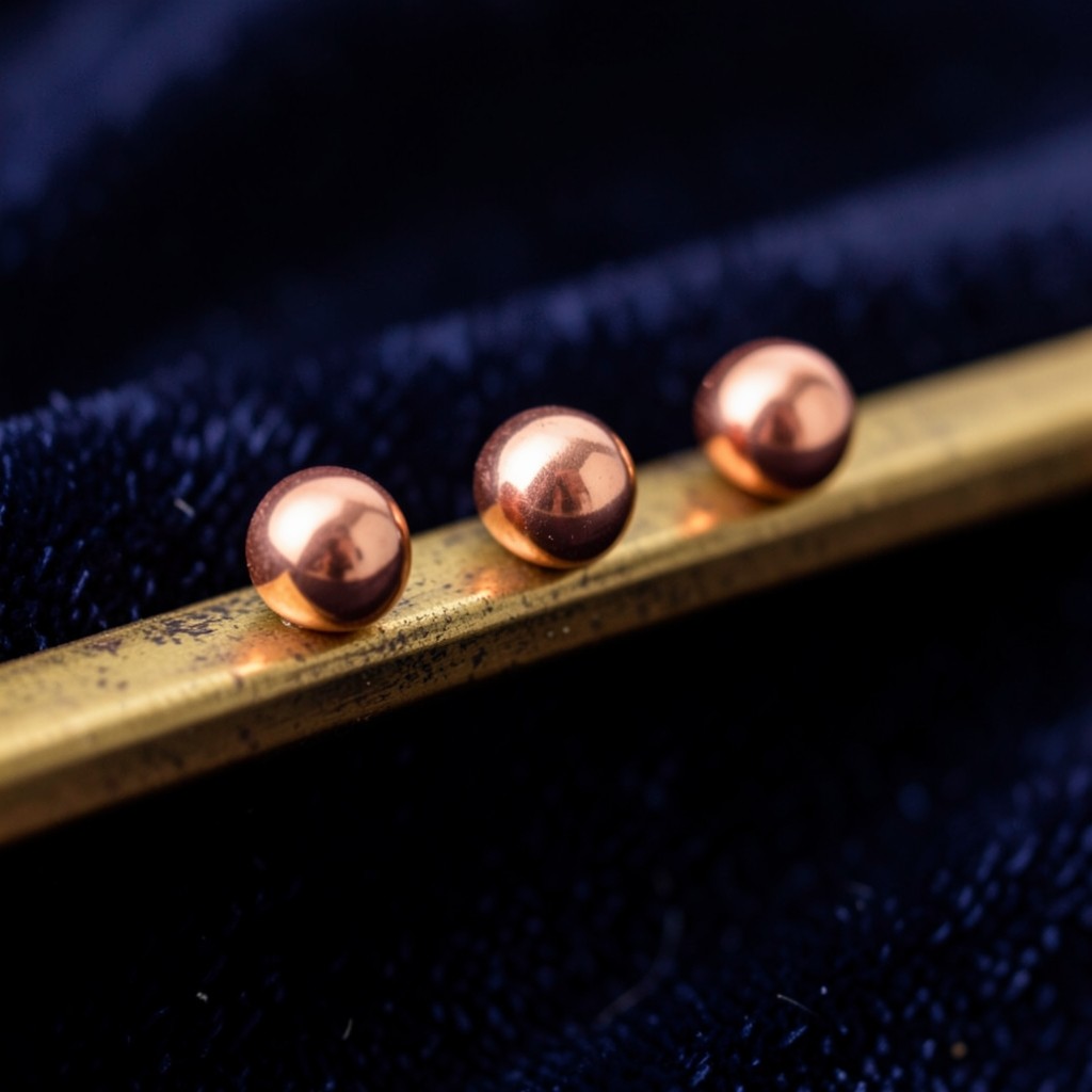 Five copper beads on a brass rail, with one bead set slightly apart from the rest